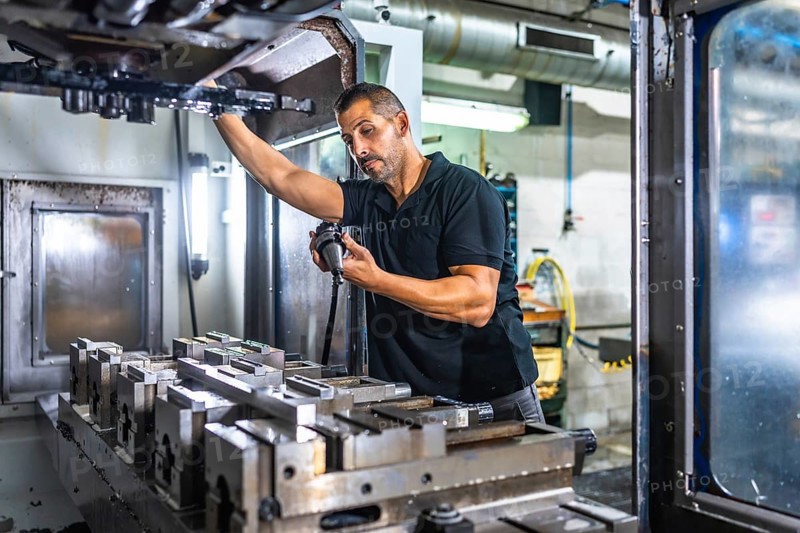 Serious male caucasian engineer inspecting a milling machine in an innovative metal cnc factory