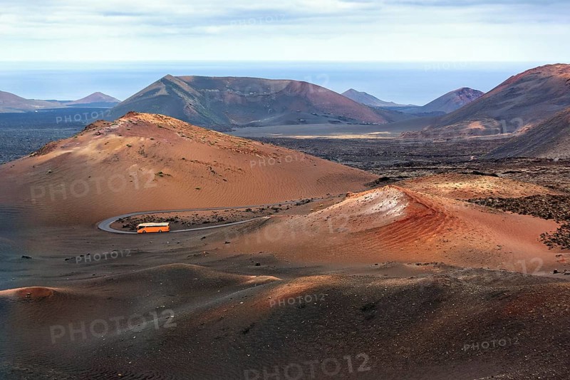 Orange-coloured coach with tourists drives through the fire mountains of Timanfaya National Park, round trip, Montanas del Fuego, Lanzarote, Canary Islands, Spain, Europe