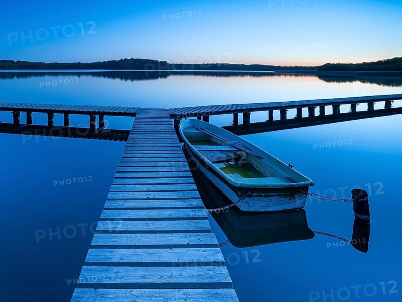 Wooden jetty with rowing boat at dusk, after sunset on Lake Schaalsee, Mecklenburg-Western Pomerania, Germany, Europe