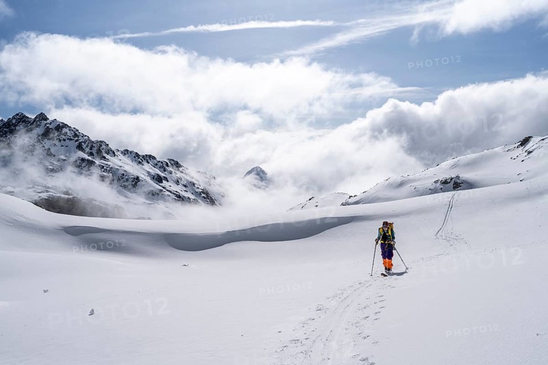 Atmospheric clouds in a wintry mountain landscape, ski tourer on the ascent to Porta d'Es-cha, Bündner Haute Route ski tour, Albula Alps, Rhaetian Alps, Grisons, Eastern Switzerland, Switzerland, Europe