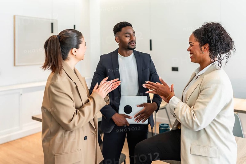 Business colleagues clapping and discussing during a productive meeting in a modern office