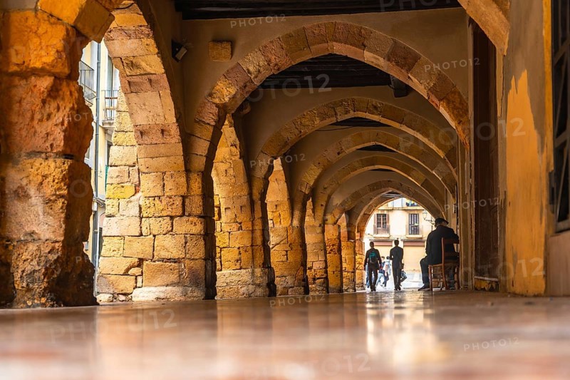 Tourists walking through the arches of the medieval city of tarragona, spain, enjoying the historical architecture