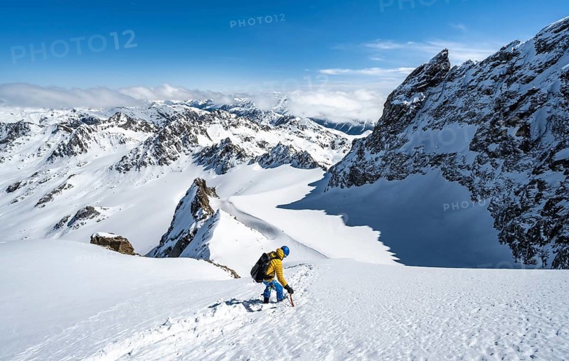 Mountaineer with ice axe and crampons, ascent through steep snowfield to Piz Kesch or Piz d'Es-cha in winter, view of mountain panorama with Vadret da Porchabella glacier, Albula Alps, Rhaetian Alps, Grisons, Eastern Switzerland, Switzerland, Europe