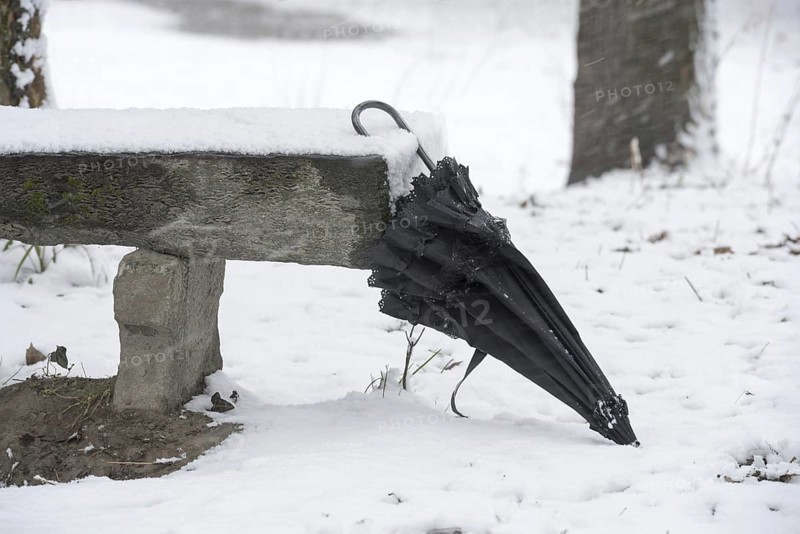 Umbrella Leaning on a Bench with Snow in Winter in a Park in Locarno, Ticino, Switzerland, Europe