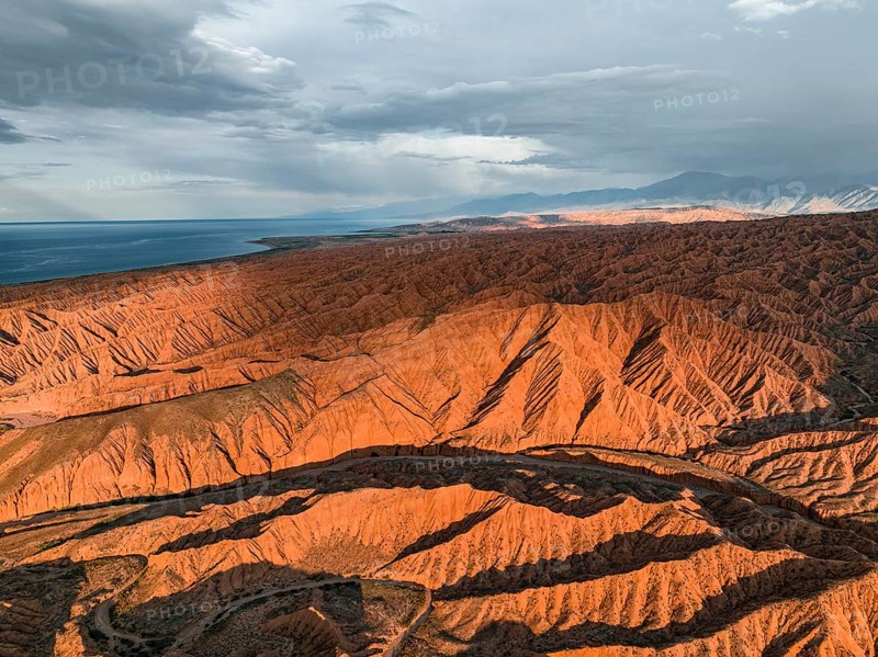 Landscape of eroded hills, badlands at sunset, Issyk Kul Lake in the background, aerial view, Canyon of the Forgotten Rivers, Issyk Kul, Kyrgyzstan, Asia