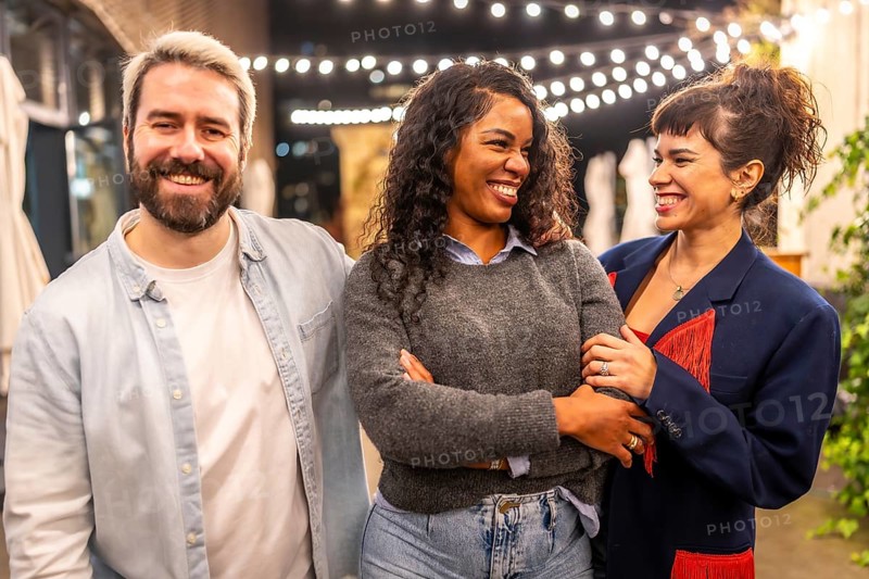 Multi-ethnic millennial friends smiling standing on night bar terrace celebrating a party