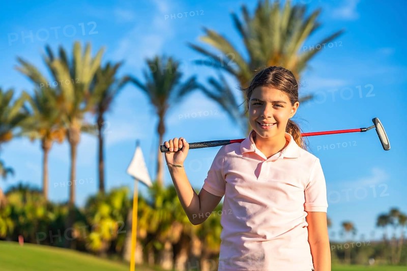 Horizontal close-up portrait of a girl with golf club on shoulder