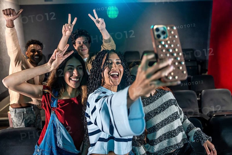 Young people taking a selfie at the movie theater during a disco dance event, having fun and enjoying the moment
