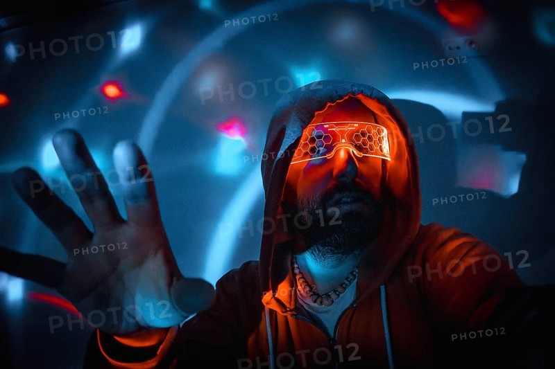 Bearded man with futuristic orange glasses interacting with holographic interface in virtual reality environment