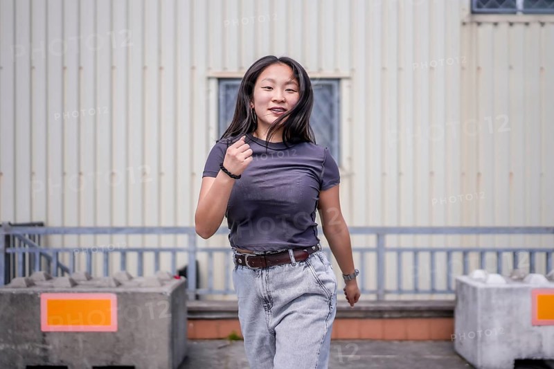Passionate asian woman dancing k-pop choreography in the city next to an industrial building