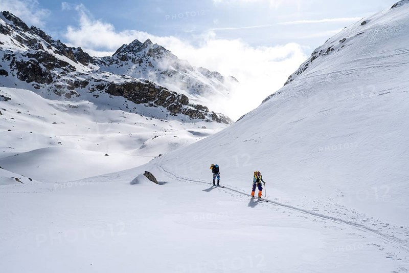 Atmospheric clouds in a wintry mountain landscape, ski tourers on the ascent to Porta d'Es-cha, Grisons Haute Route ski tour, Albula Alps, Rhaetian Alps, Grisons, Eastern Switzerland, Switzerland, Europe
