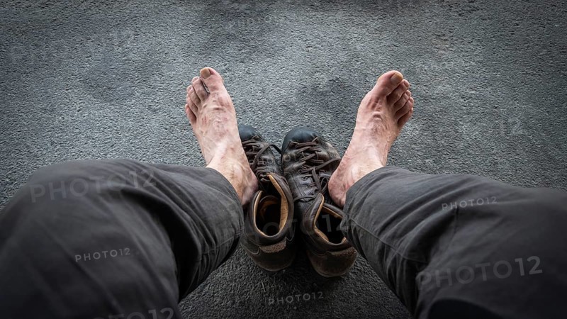 View of two bare feet of a pilgrim, worn hiking boots on dark ground, pilgrimage route Olavsweg or Olavsleden, Hamar, Norway, Europe