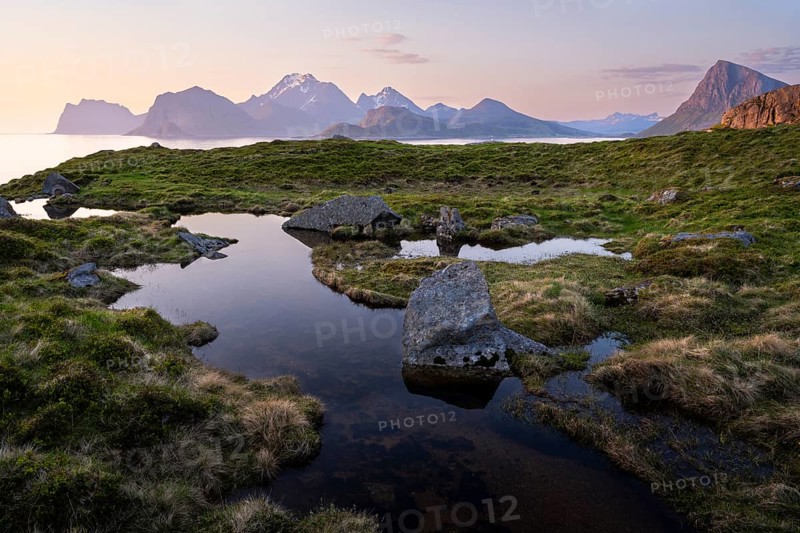 Landscape at Stornappstinden mountain. Foothills of a stream in the foreground. View of the mountains Hogskolmen, Himmeltindan, Veggen and Mannen near Haukland, Offersoykammen on the right. At night at the time of the midnight sun in good weather. Early summer. Flakstadoya, Lofoten, Norway, Europe