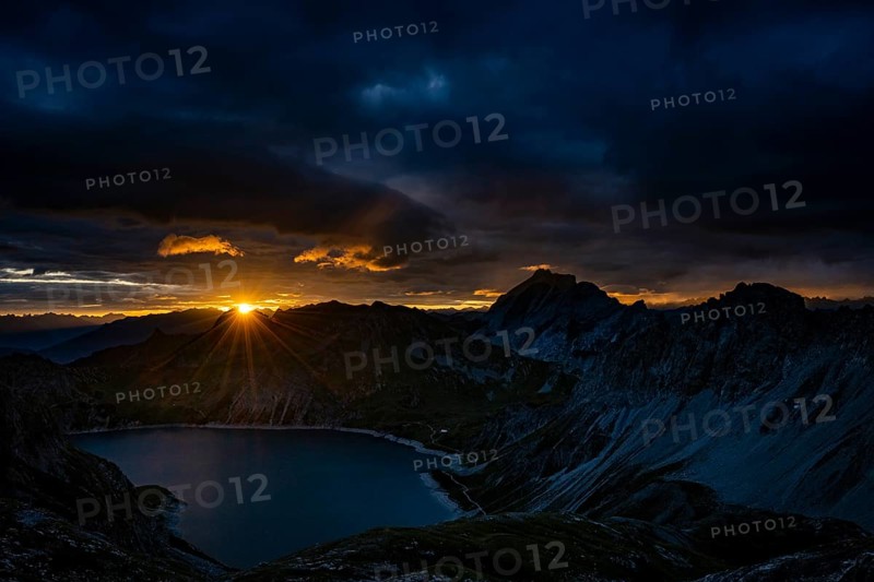 Lake Lüner See with Montafon mountains and dramatic cloudy sky at sunrise, Tschagguns, Rätikon, Montafon, Vorarlberg, Austria, Europe