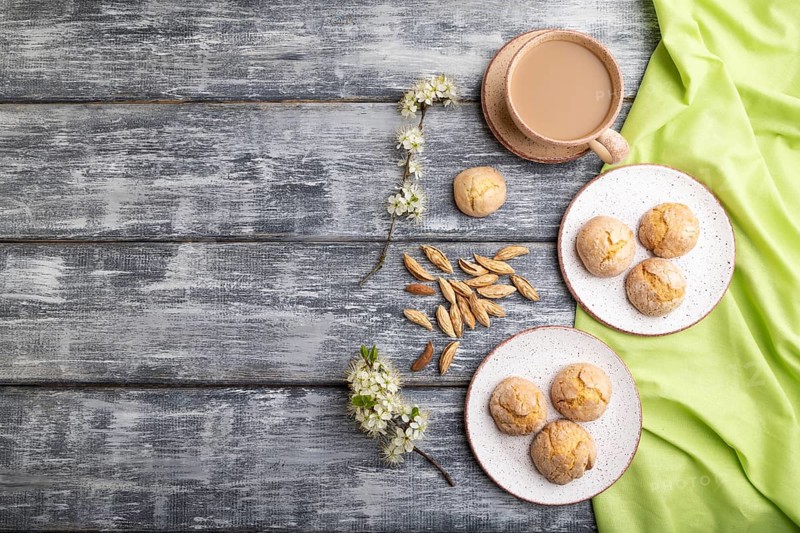 Almond cookies and a cup of coffee on a gray wooden background and green linen textile. Top view, flat lay, copy space