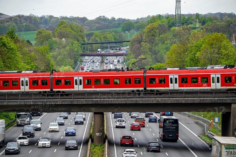 S-Bahn train crossing the motorway A3, traffic on 8 lanes, incl. the temporarily released hard shoulder, behind the motorway junction Hilden, view in north direction, near Erkrath, North Rhine-Westphalia, Germany, Europe