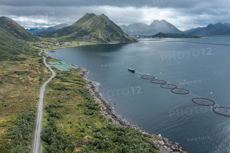 Aerial view of a salmon farm, rainy weather, grey sky, village Myre in the back, Vesteralen islands, Norway, Europe