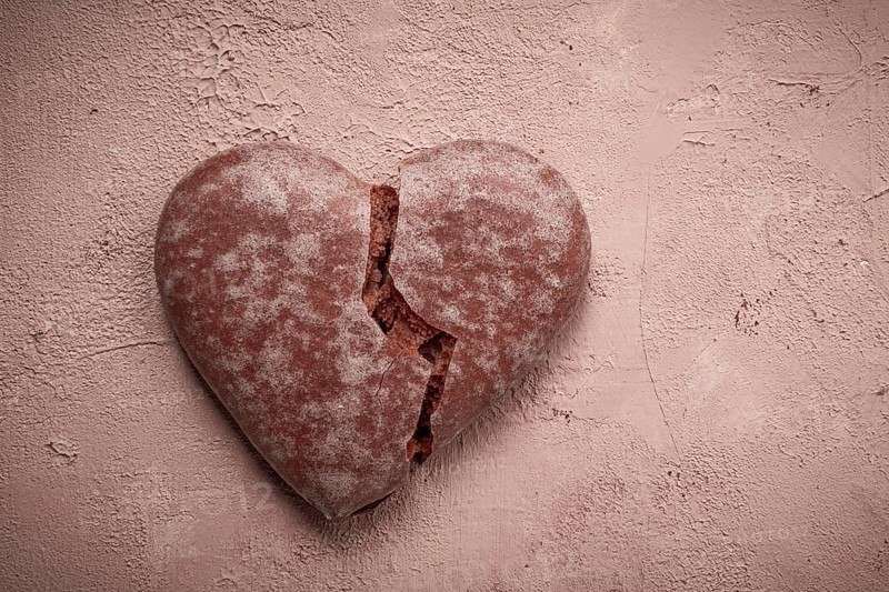 Glazed chocolate gingerbread, heart-shaped, top view, a broken heart, close-up, on beige background, no people
