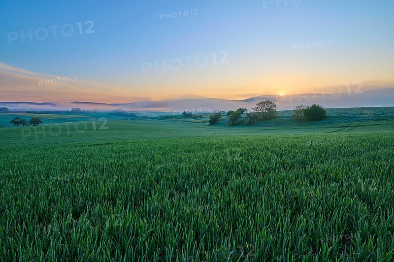 A picturesque sunrise over a wide green field and a gentle hilly landscape, Mönchberg, Mltenberg, Spessart, Bavaria, Germany, Europe