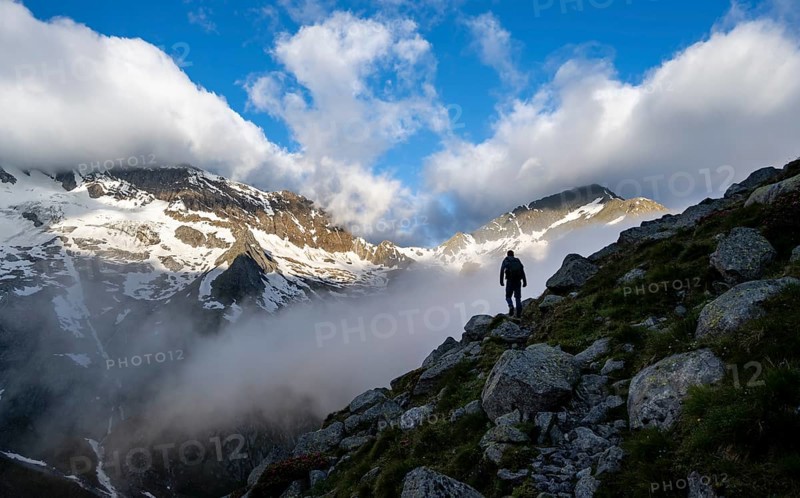 Silhouette of a mountaineer in front of a cloudy, atmospheric mountain landscape, rocky snow-covered mountains with summit Hochsteller, Furtschaglhaus, Berliner Höhenweg, Zillertal Alps, Tyrol, Austria, Europe