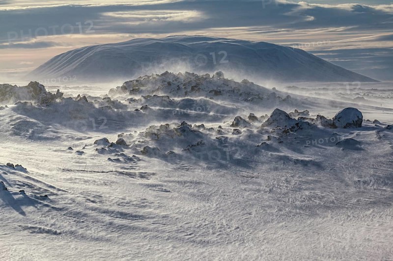 Solidified lava and stones in a snowstorm, windy, sunny, backlight, Myvatn, Iceland, Europe