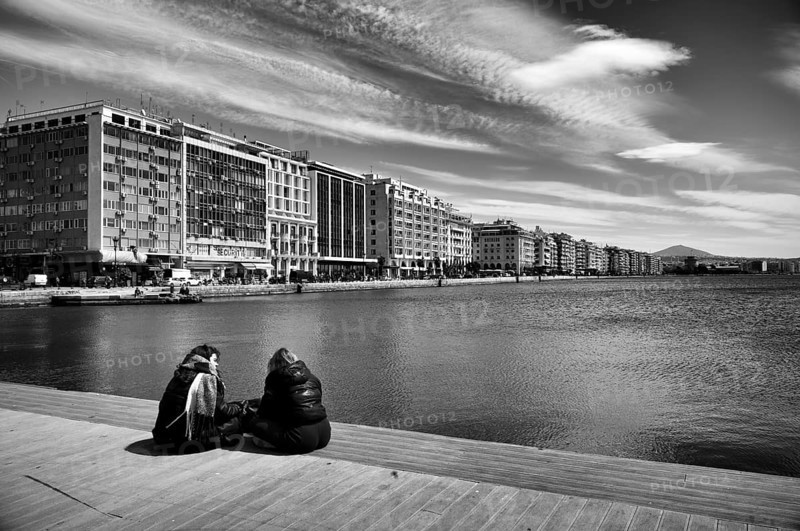 Two woman sitting on the quay, old harbour, view of the waterfront, skyline of Thessaloniki, black and white, Thessaloniki, Macedonia, Greece, Europe