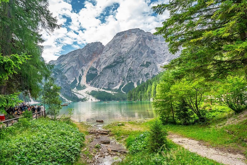 Tourists enjoying the landscape at lake braies, also called pragser wildsee, with the seekofel mountain in the background, in the dolomites, south tyrol, italy
