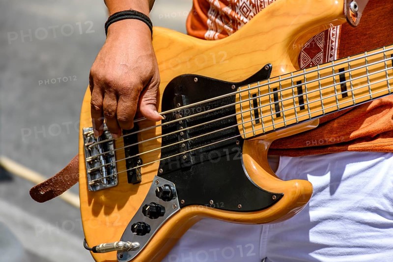 Hands playing an electric bass guitar on the street in a sunny day, Minas Gerais, Brazil, South America