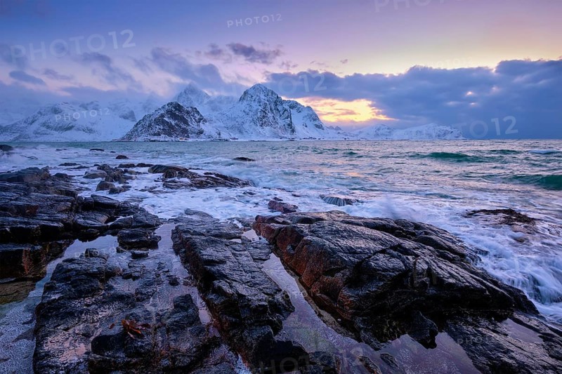 Beach of Norwegian sea on rocky coast in fjord on sunset in winter. Vareid beach, Lofoten islands, Norway, Europe