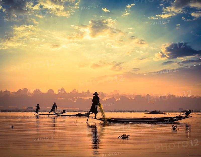 Myanmar travel attraction landmark, traditional Burmese fishermen sihouettes at Inle lake on sunset, Myanmar famous for their distinctive one legged rowing style