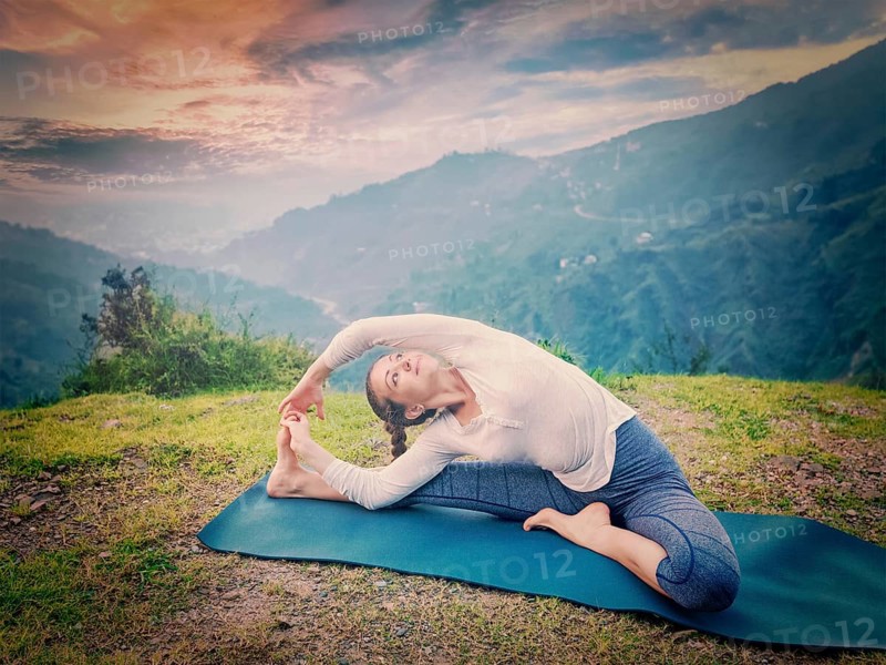 Yoga outdoors, young sporty fit woman doing Hatha Yoga asana janu sirsasana, Revolved Head-to-Knee Pose, in. Vintage retro effect filtered hipster style image