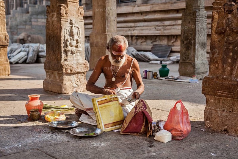 MADURAI, INDIA, FEBRUARY 16, 2013: Indian brahmin (traditional Hindu society) priest with donation in famous Meenakshi Amman Temple, historic Hindu temple located in temple city Madurai