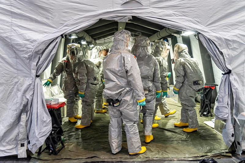 Decontamination of injured persons after an assumed accident involving hazardous substances, fire brigade and aid organisations practise setting up and operating a decontamination station, injured persons are sighted and then washed in a special shower tent to remove possible hazardous substances and chemicals in order to avoid further injuries, the emergency services wear special, ventilated protective suits, large-scale exercise by the Essen fire brigade