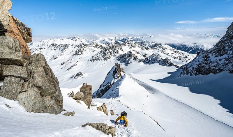 Mountaineer with ice axe and crampons, ascent through steep snowfield to Piz Kesch or Piz d'Es-cha in winter, view of mountain panorama with Vadret da Porchabella glacier, Albula Alps, Rhaetian Alps, Grisons, Eastern Switzerland, Switzerland, Europe