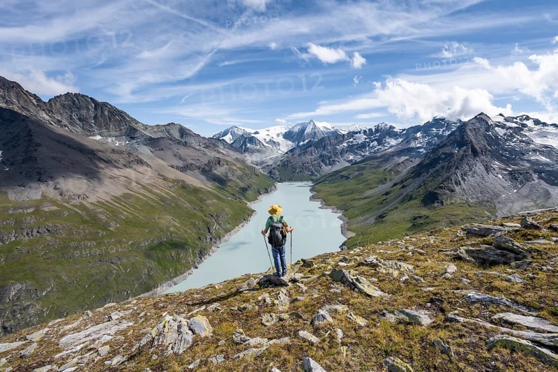 Mountaineer on the summit of Mont de la Blana, view of a blue mountain lake, Lac des Dix reservoir, behind mountain peak Mont Blanc de Cheilon with glacier, Hérménence, Valais Alps, Valais, Switzerland, Europe