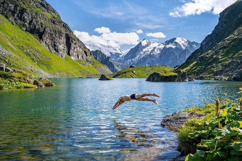 Man taking a header, cooling off while swimming in the mountain lake Lac de Louvie, behind the summit of the Grand Combin, Val de Bagnes, Valais, Switzerland, Europe