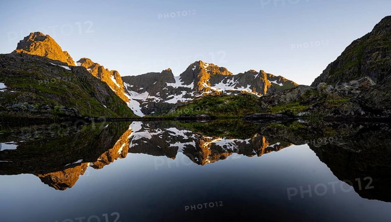 Rocky mountain peaks reflected in a small pond, mountain landscape with alpenglow at sunrise, at the Trollfjord Hytta, at the Trollfjord, Lofoten and Vesterålen, Nordland, Norway, Europe