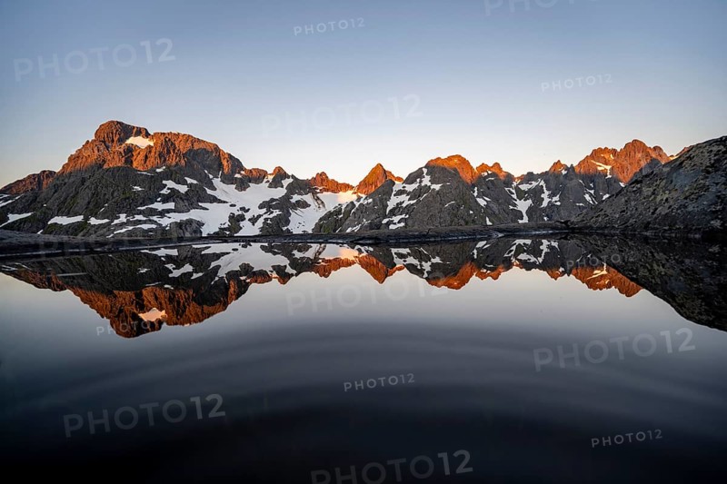Rocky mountain peaks reflected in a small pond, mountain landscape with alpenglow at sunrise, at the Trollfjord Hytta, at the Trollfjord, Lofoten and Vesterålen, Nordland, Norway, Europe