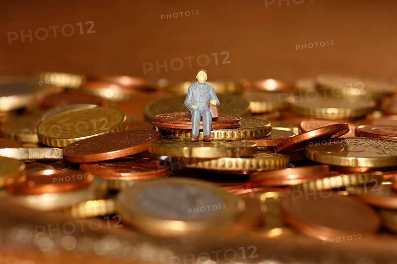 Miniature man sitting among euro coins, North Rhine-Westphalia, Germany, Europe