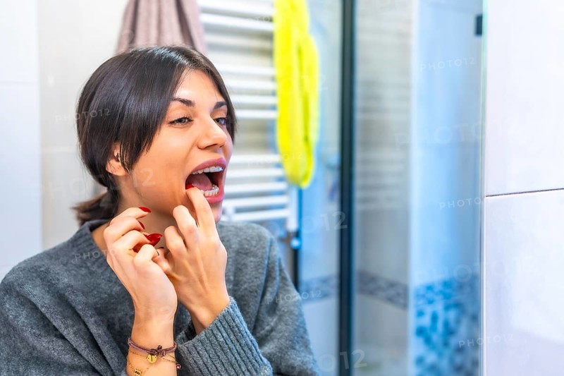 Caucasian adult beauty woman placing transparent brackets in the toilet at home