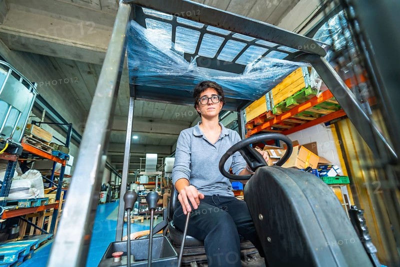 Frontal low angle view of a caucasian woman working in metallurgic factory driving a forklift