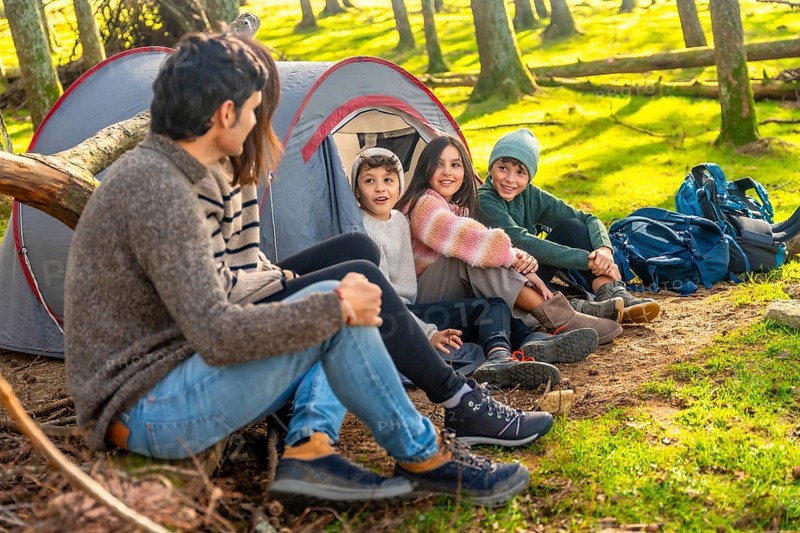 Caucasian family with three child enjoying a weekend camping in the forest together
