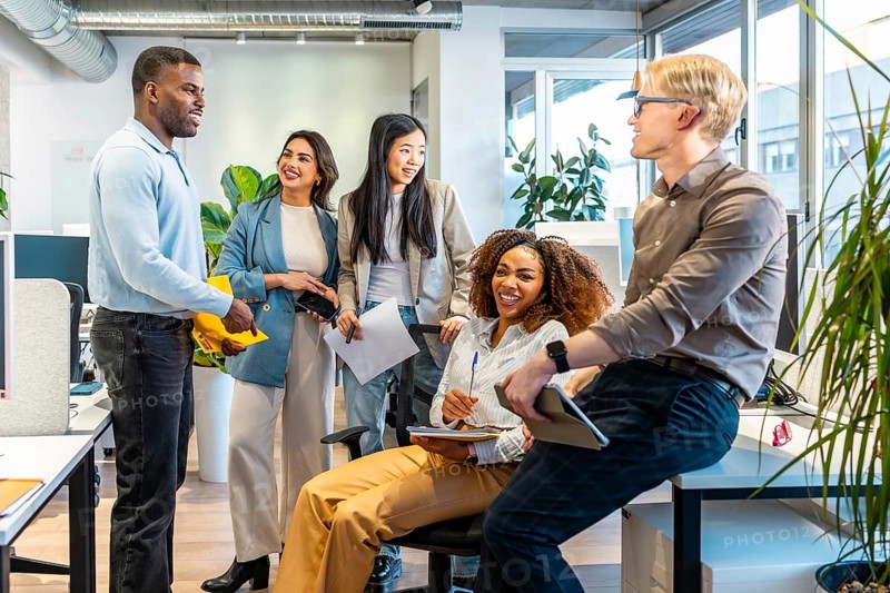 Diverse colleagues interacting, sharing ideas, and working together in a bright, open plan office space