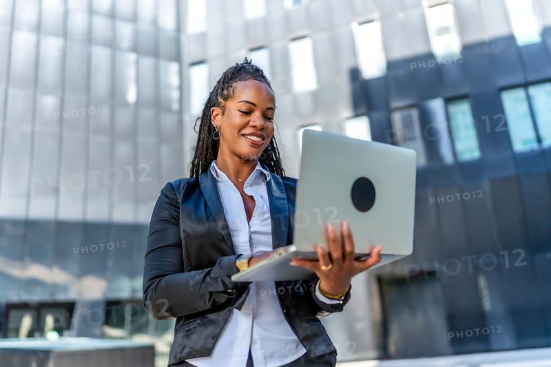 Portrait of a beauty confident latin businesswoman standing using laptop outside a financial building