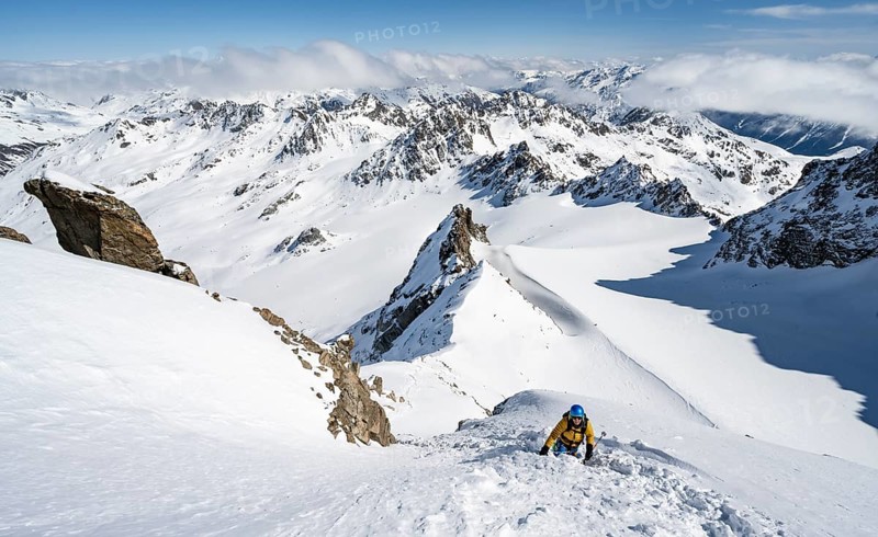 Mountaineer with ice axe and crampons, ascent through steep snowfield to Piz Kesch or Piz d'Es-cha in winter, view of mountain panorama with Vadret da Porchabella glacier, Albula Alps, Rhaetian Alps, Grisons, Eastern Switzerland, Switzerland, Europe