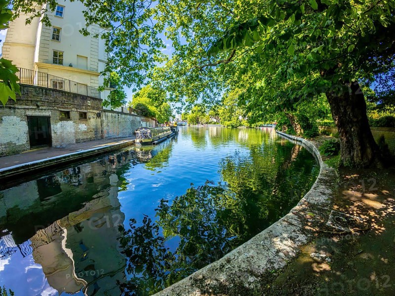 Calm waters reflecting buildings and lush trees along little venice canal in london, offering a peaceful urban oasis