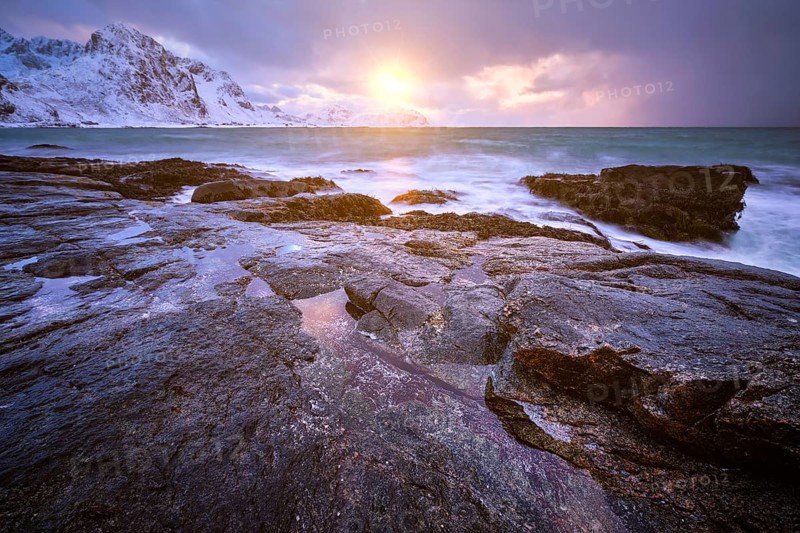 Beach of Norwegian sea on rocky coast in fjord on sunset in winter. Vareid beach, Lofoten islands, Norway, Europe