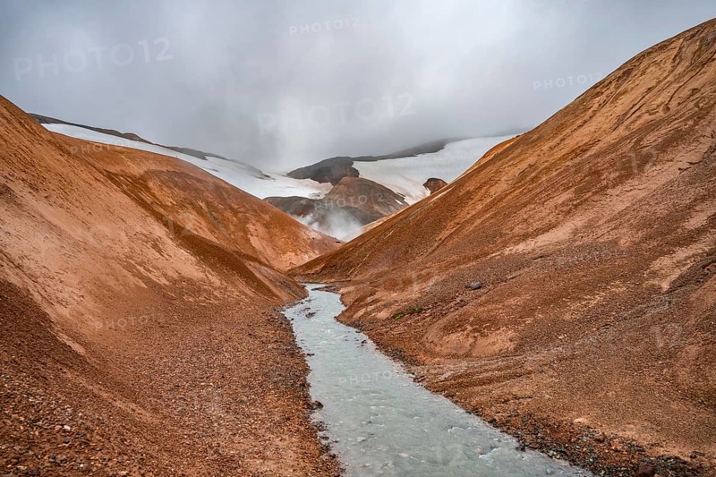 Steaming stream between colourful rhyolite mountains and snowfields, Hveradalir geothermal area, Kerlingarfjöll, Icelandic Highlands, Iceland, Europe
