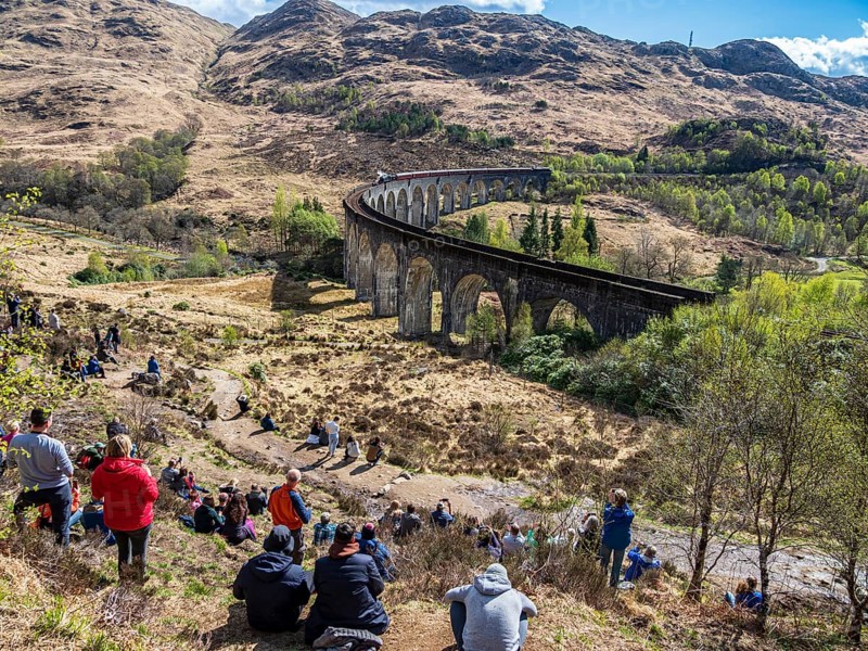 Tourists waiting for the jacobite steam train at the Glenfinnan viaduct, scottish highland, Scotland, UK