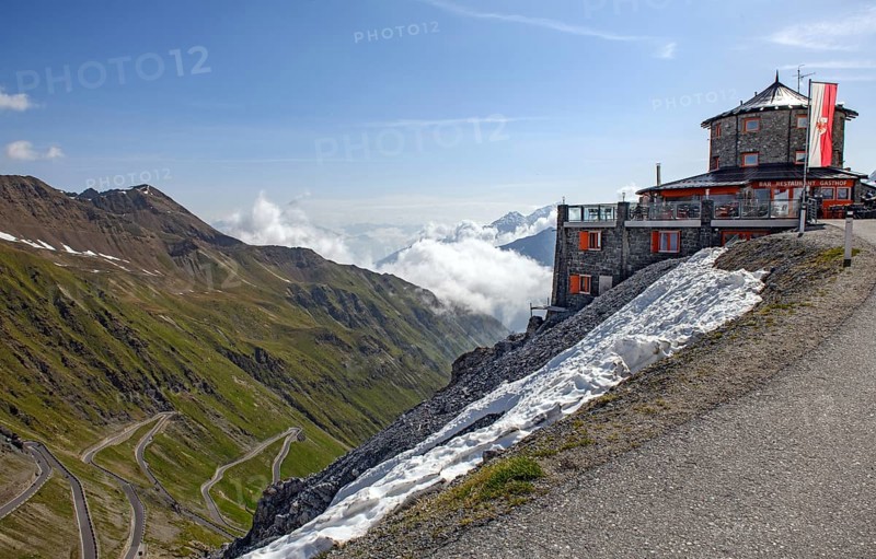 Right historic mountain hotel Hotel Restaurant Bar Gasthof Alpengasthof in Tibetan architectural style Tibetan house in front Flag Flag of South Tyrol at 2800 metres above sea level in the background East ramp North ramp Ascent to Alpine pass Alpine pass road Pass road with serpentines tight bends Stelvio Pass Stelvio, Stelvio, South Tyrol, Alto Adige, Italy, Europe